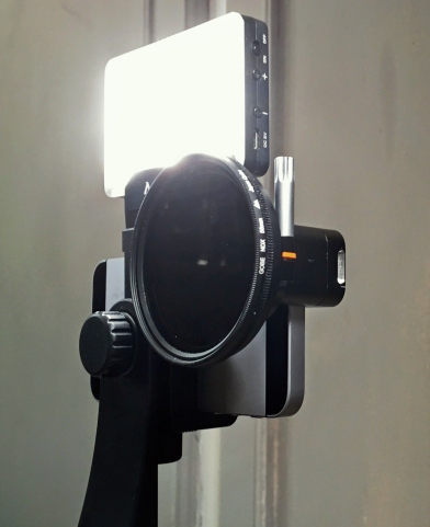 One of our iPhones with Moondog lens plus ND filter and Aputure mini light attached.